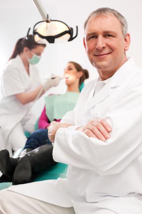 doctor smiling with patient being worked on in background | jonesboro dentist