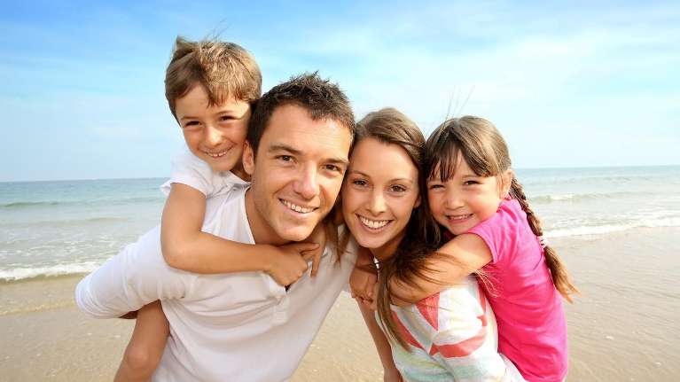 A smiling family at the beach | family dentist 72401