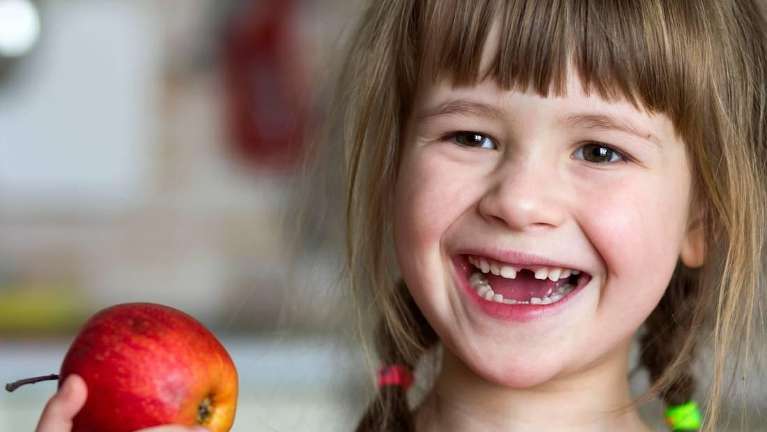 Smiling child eating an apple