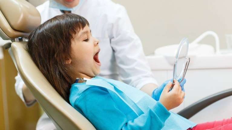 A child at the dentist looking at her teeth