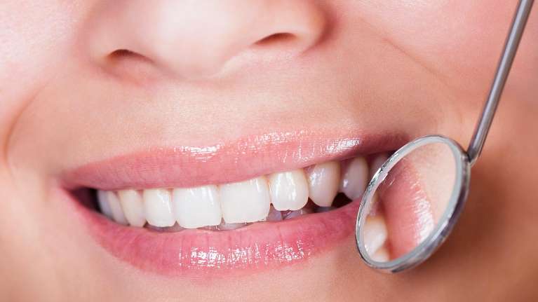 A person smiling with a dental mirror | Jonesboro dentist