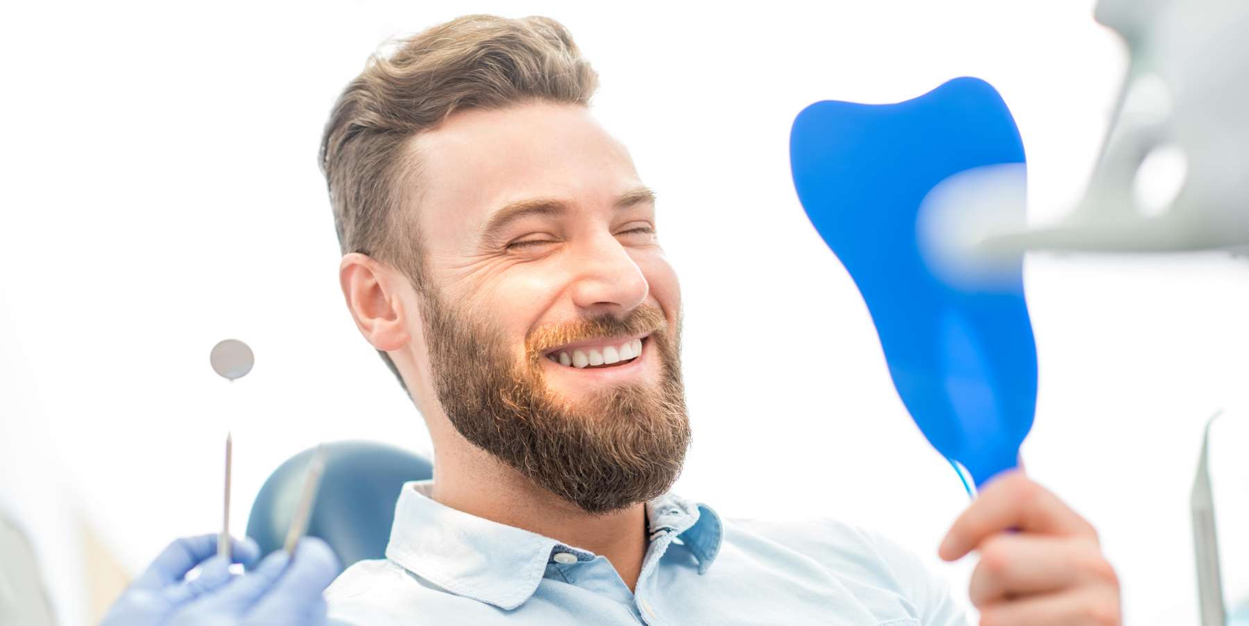 A man happily examining his smile | top Jonesboro dentist